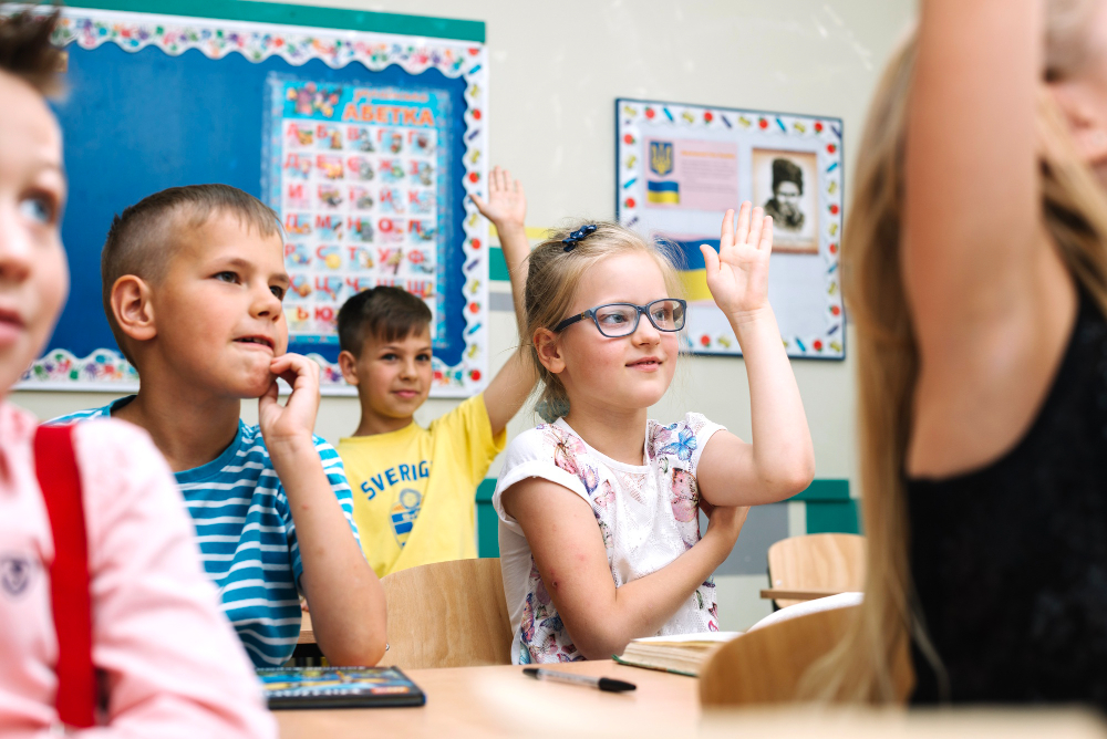 Kids raising their hands confidently in class
